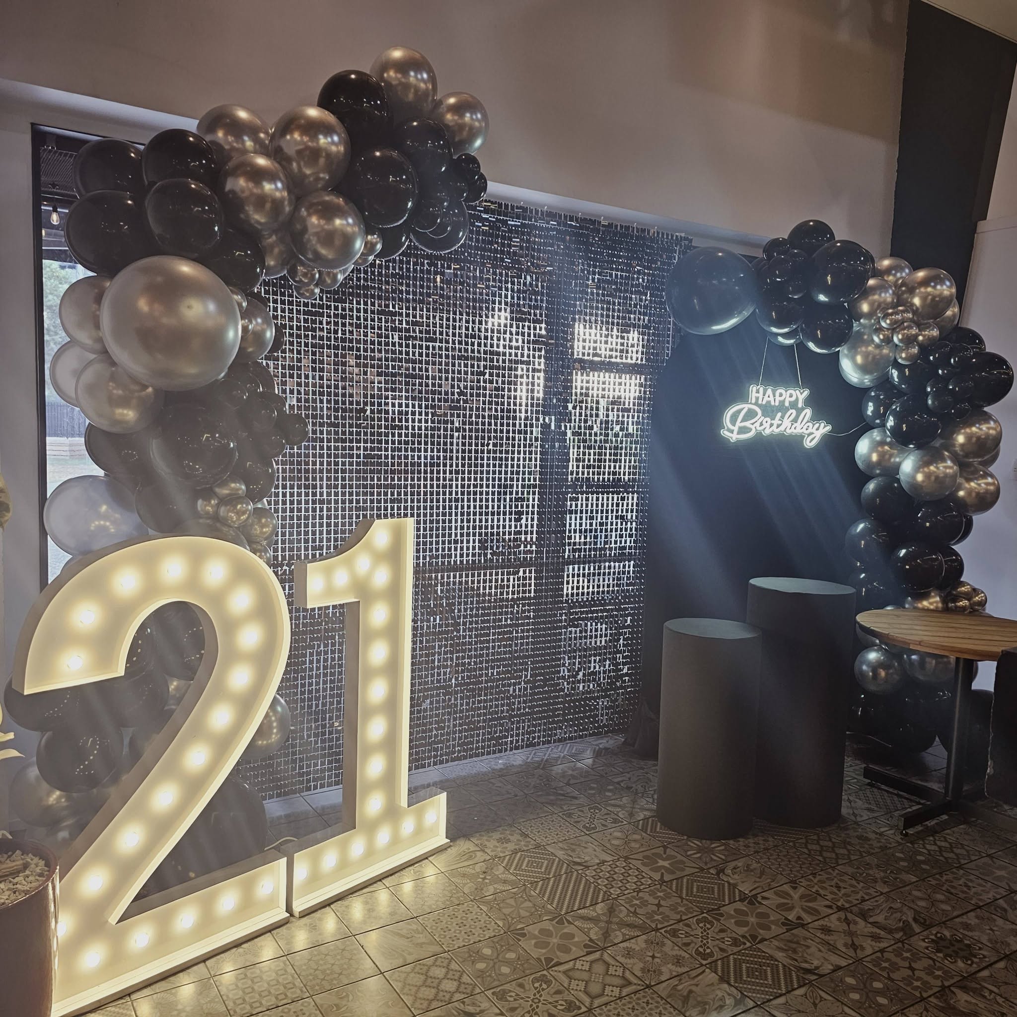 Black and gold 21st birthday balloon setup with light-up numbers